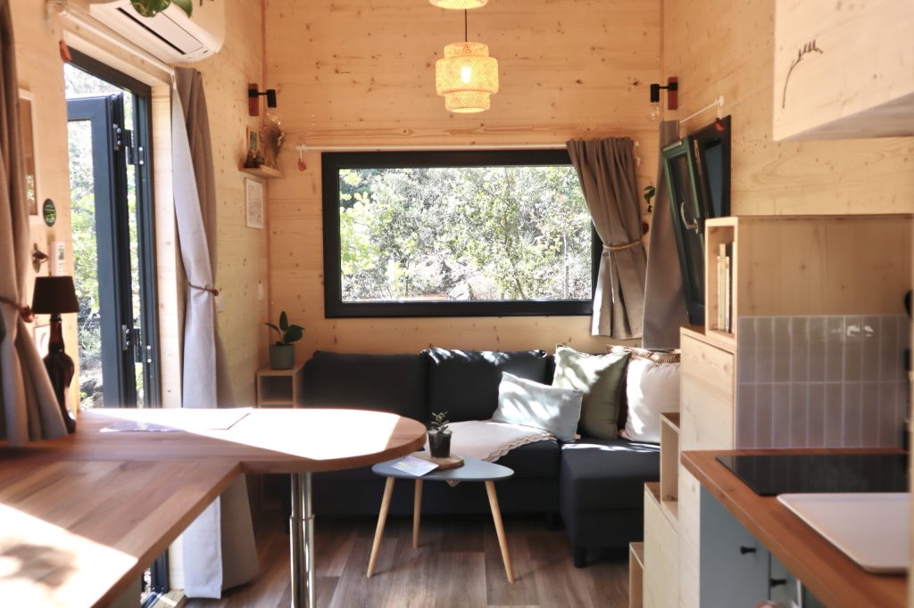 Pièce de vie de la Tiny House Basalte avec espace repas et canapé d'angle
