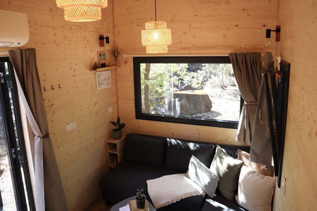 Salon de la Tiny House Basalte avec canapé d'angle convertible